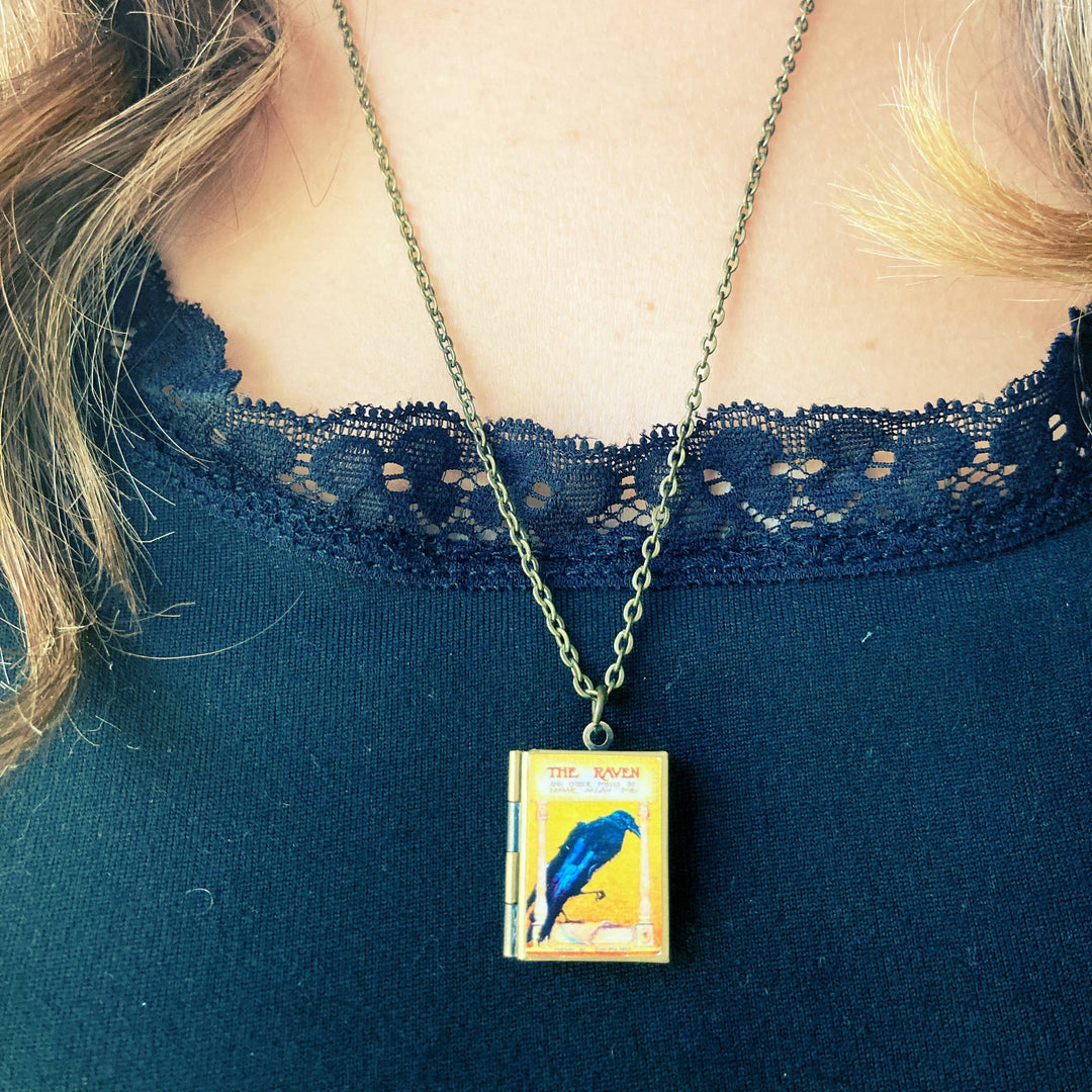 Necklace with a pendant featuring a blue bird design on a person wearing a blue lace top.