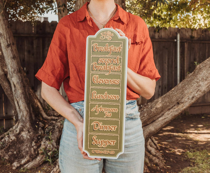 Person holding a sign with meal times on it outdoors.