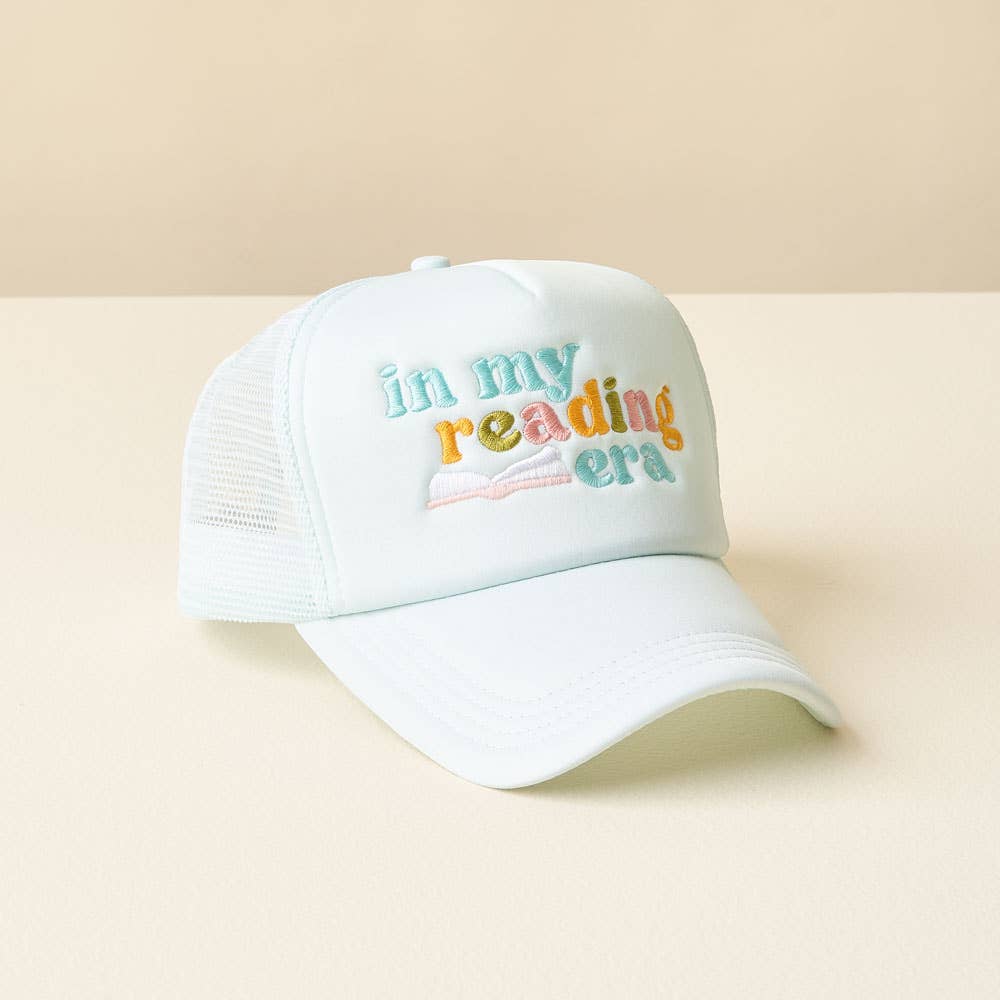 White cap with colorful text 'in my reading era' on a beige background