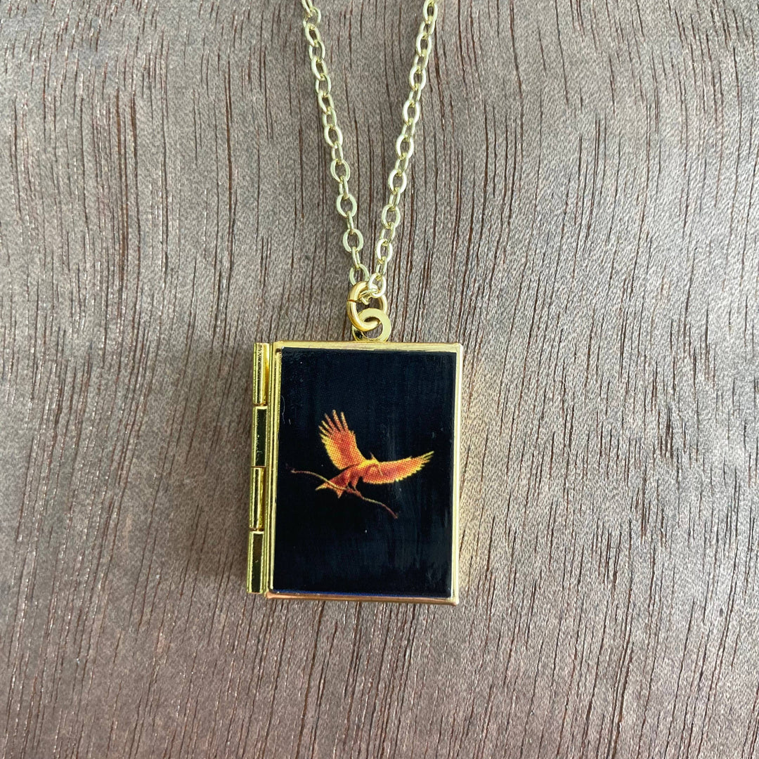 Necklace with a pendant featuring a bird design on a wooden surface