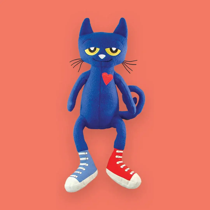 Blue cat plush toy with red heart and shoes on a peach background