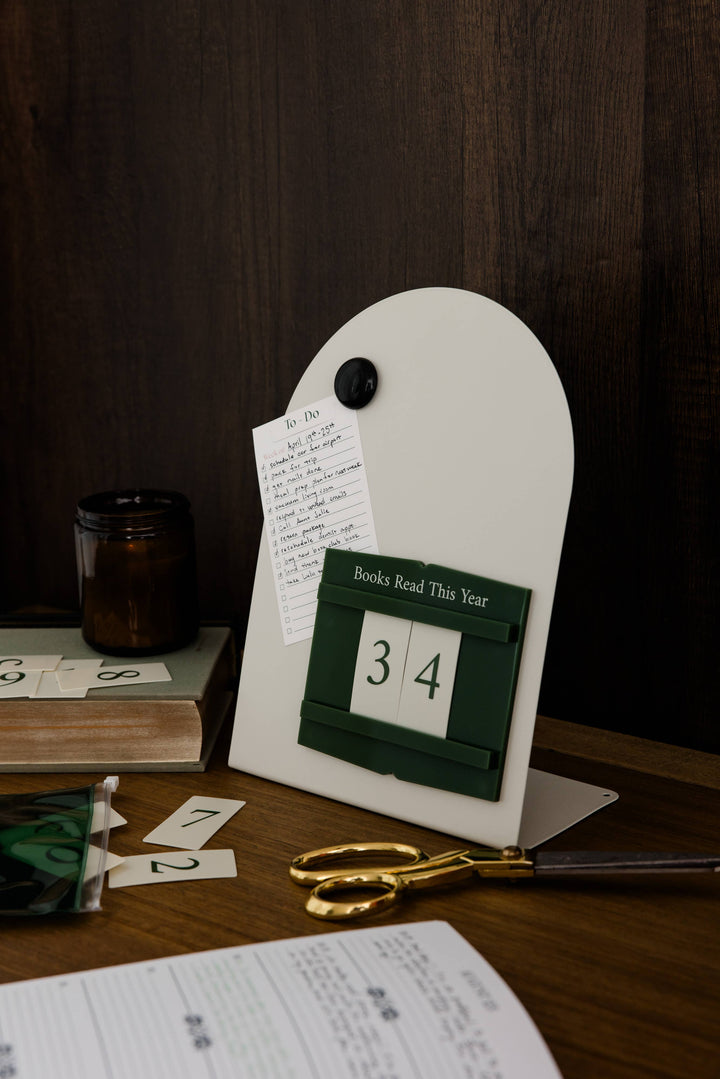 A white arched bookish desk organizer with a dark green flap calendar showing 34 and the words &