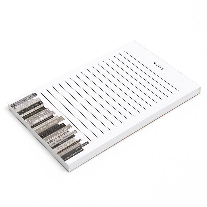 Notepad with lined pages and a set of metallic pens on a white background