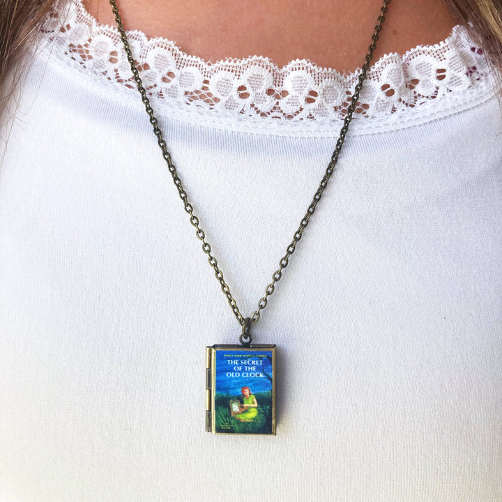 Necklace with a book-shaped pendant on a white lace-trimmed top