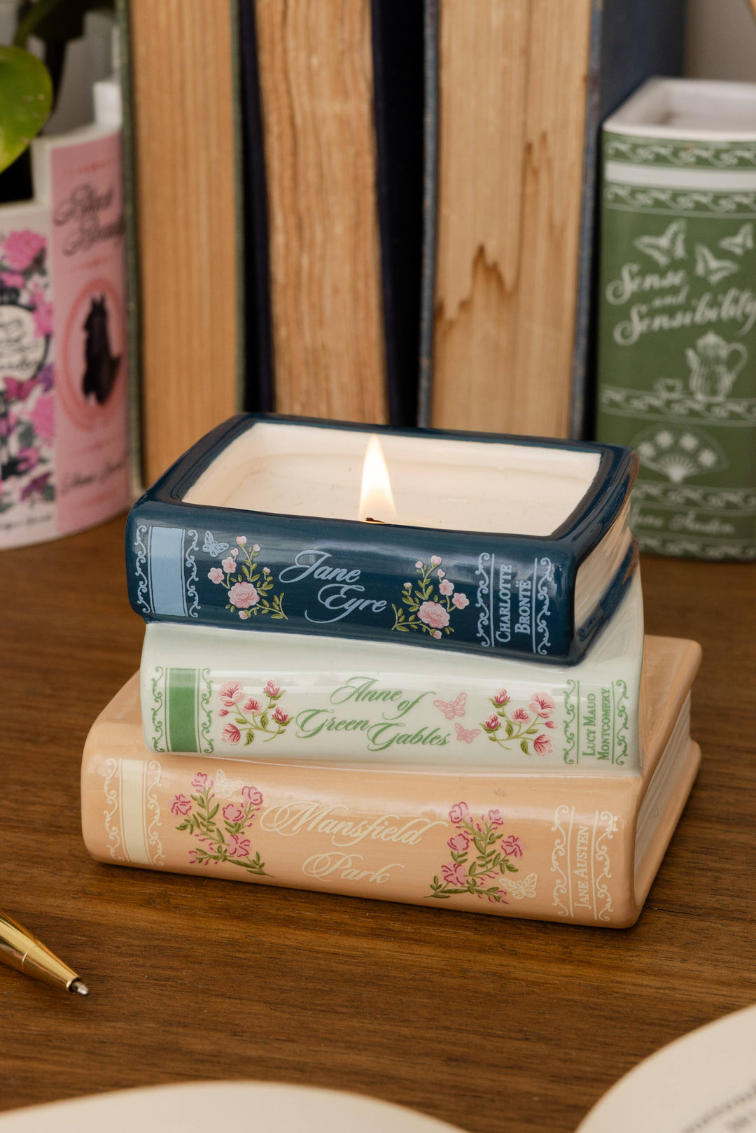 A square candle in a dark blue tin with floral detailing and the name &