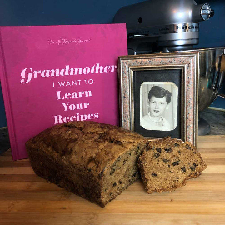 Bread loaf with a framed photo and pink book on a wooden surface