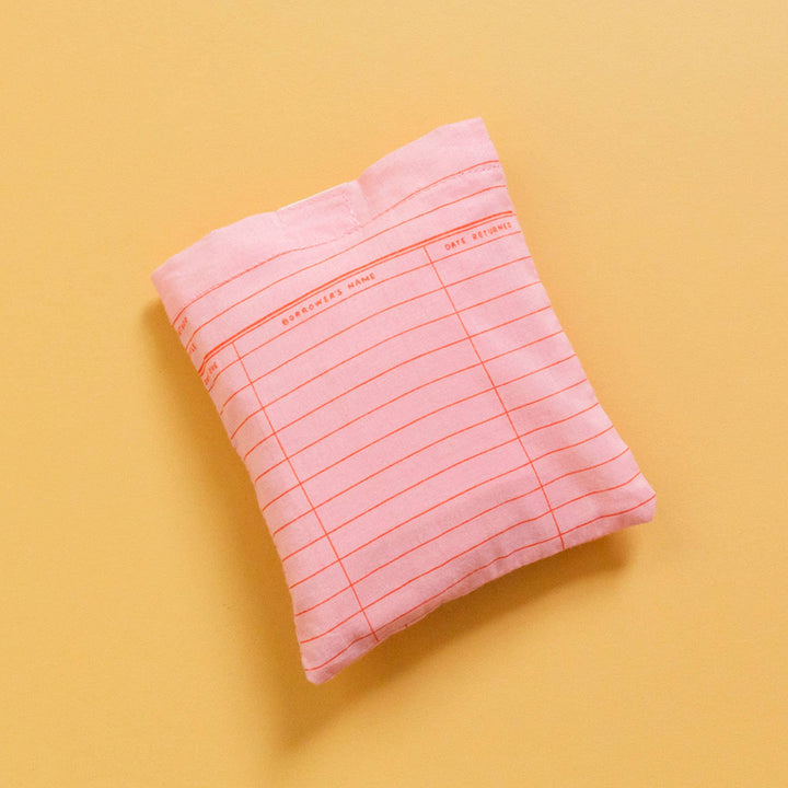 Pink pillow with grid pattern on a yellow background
