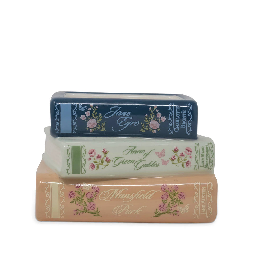 Three decorative book-shaped items stacked vertically on a white background, featuring floral designs and titles including Jane Eyre, Anne of Green Gables, and Mansfield Park.