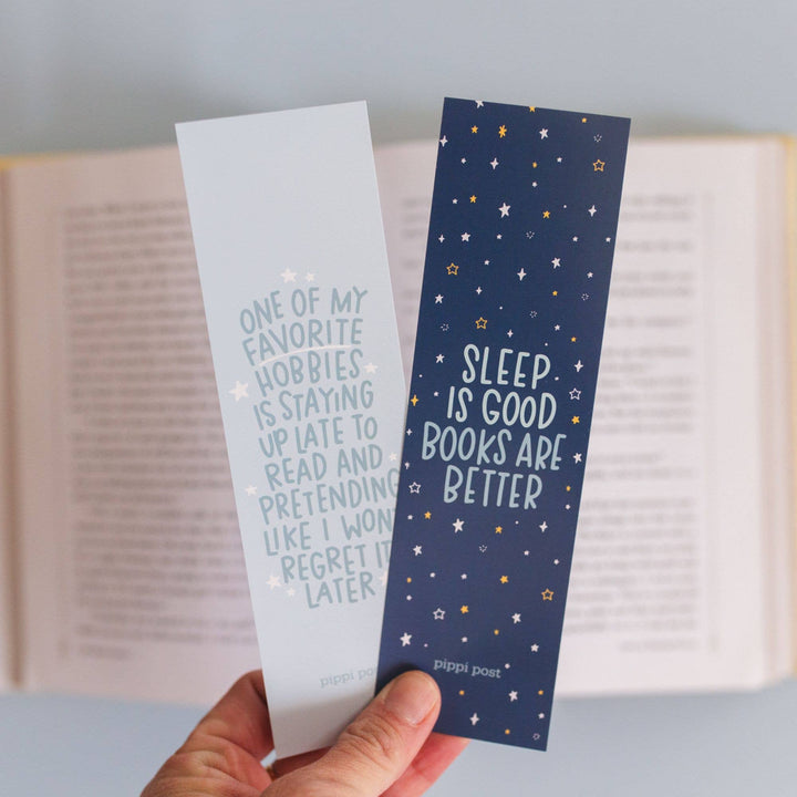 Two bookmarks held in front of an open book with text and star designs.