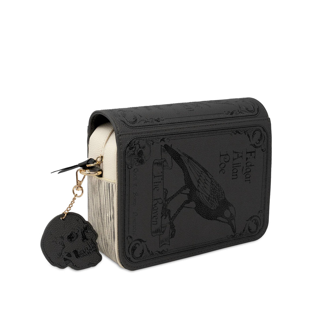 A black faux-leather book-style clutch or wallet featuring embossed gothic artwork of a raven and the text &