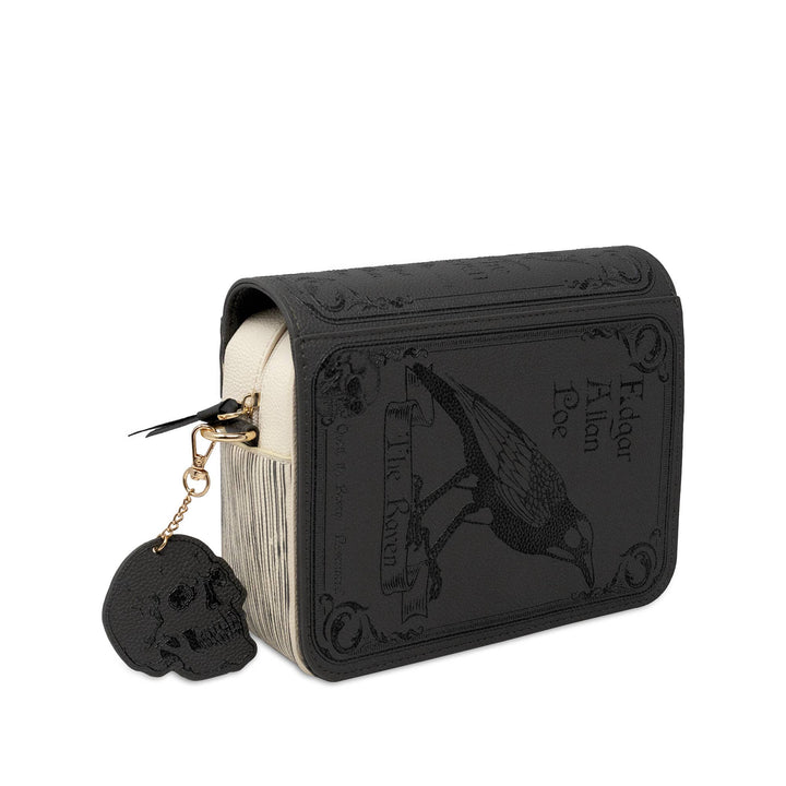 A black faux-leather book-style clutch or wallet featuring embossed gothic artwork of a raven and the text &