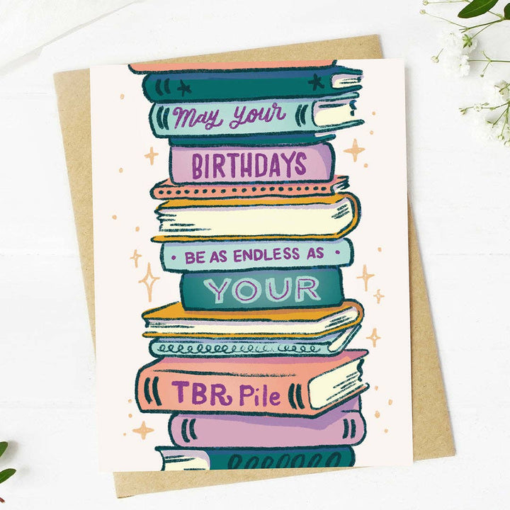 Greeting card with a stack of books and text on a white background. Text reads &
