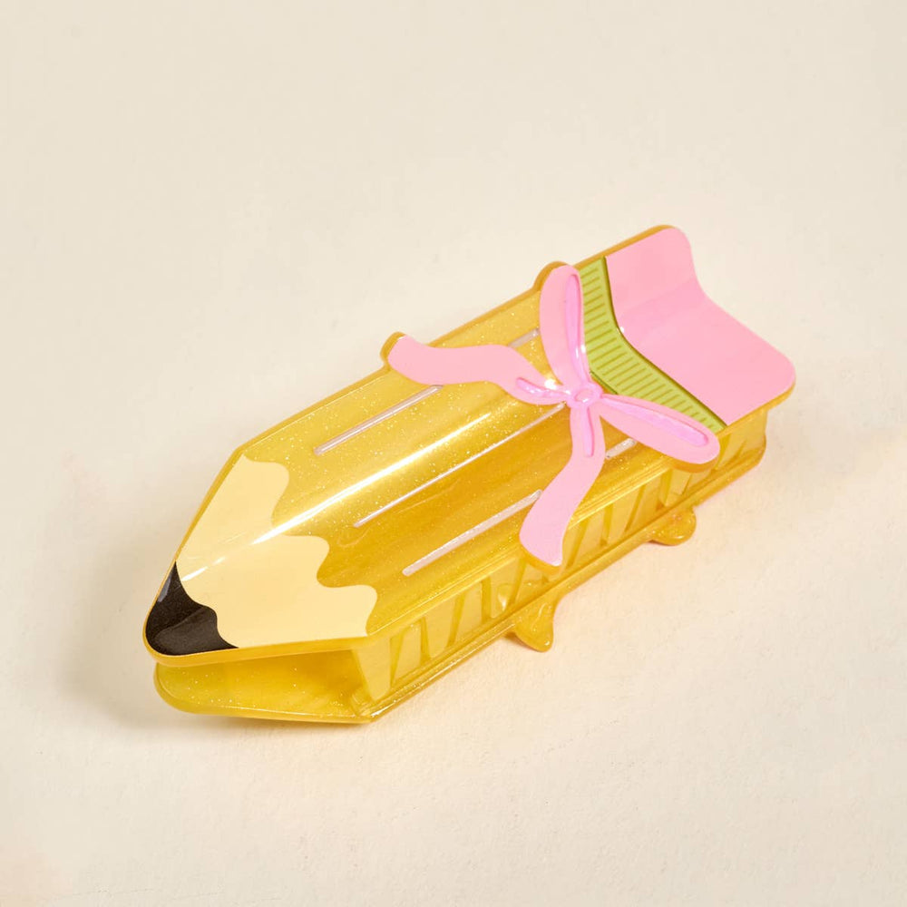 Yellow pencil-shaped cookie cutter with a pink handle on a beige background