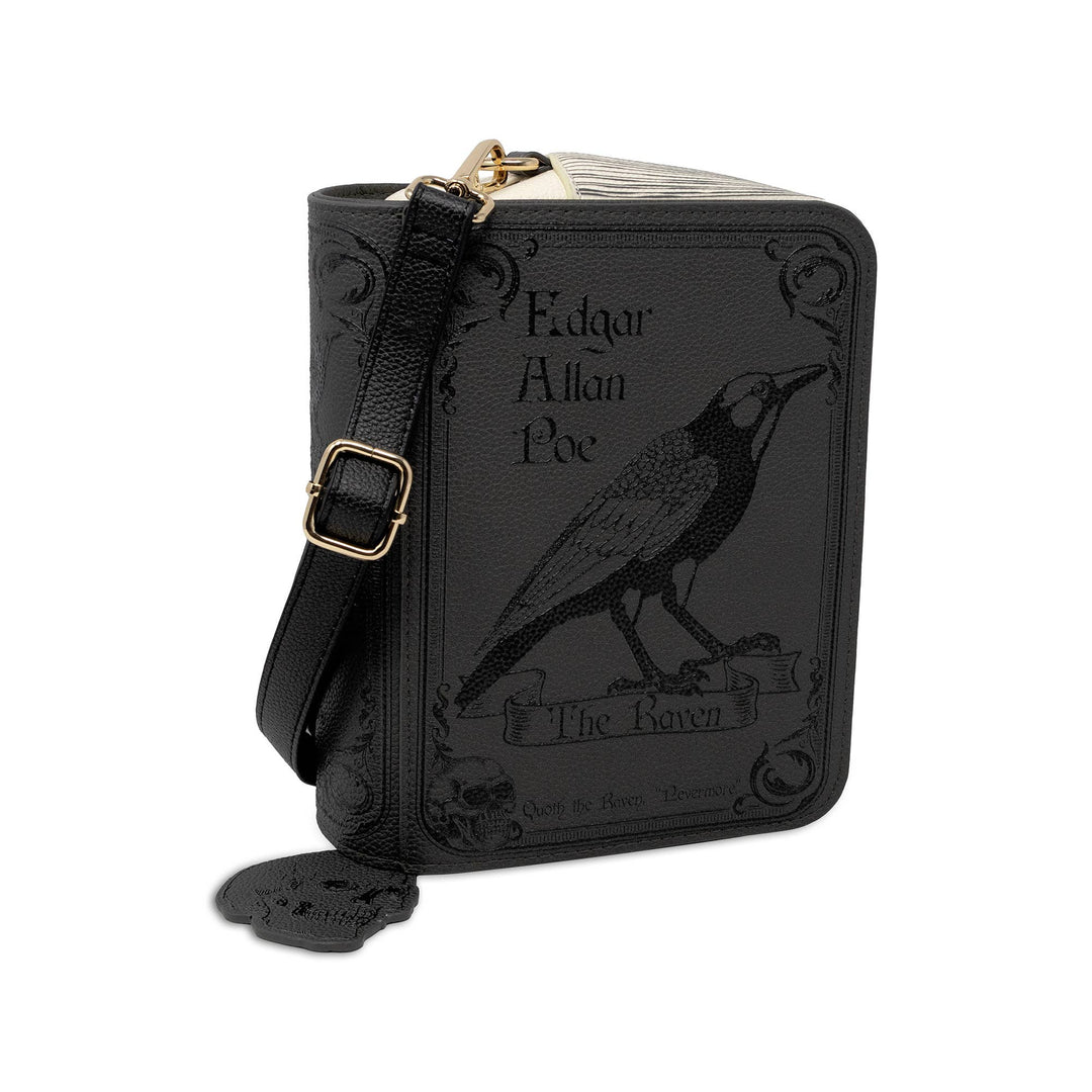 A black faux-leather crossbody bag styled like a vintage book cover, featuring an embossed raven and the text &