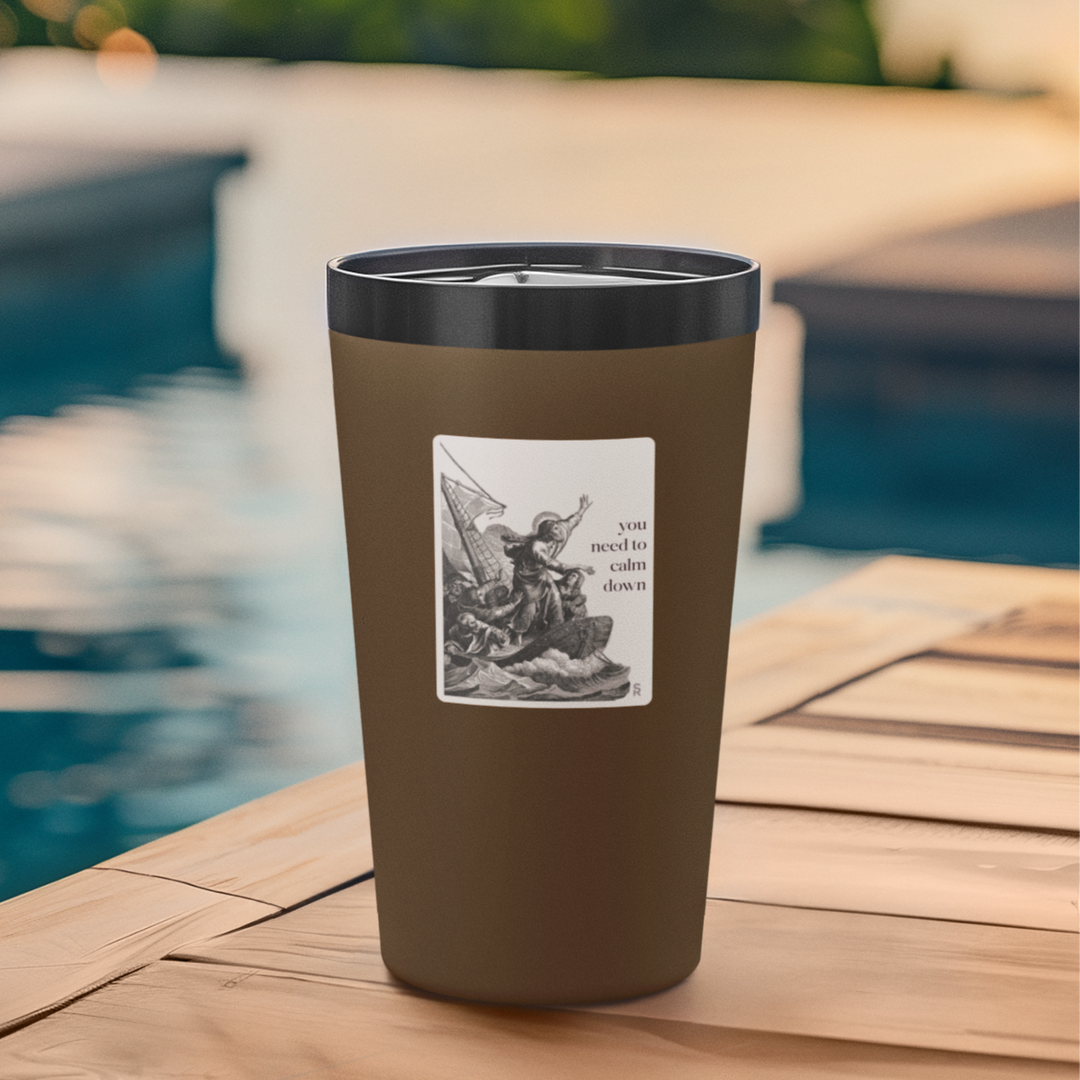 Brown tumbler with a black lid and graphic design on a wooden surface by a pool.