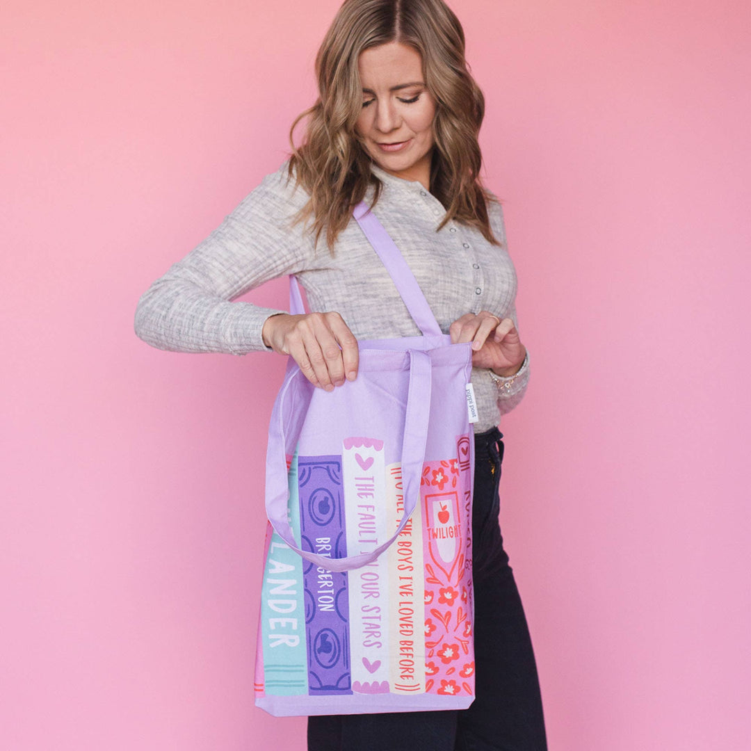 Woman holding a colorful tote bag against a pink background
