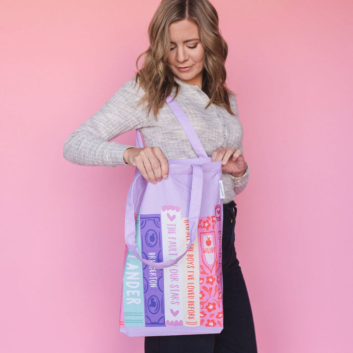 Woman holding a colorful tote bag against a pink background