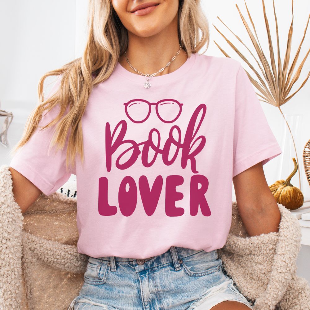 Person wearing a pink t-shirt with 'Book Lover' text and glasses graphic.