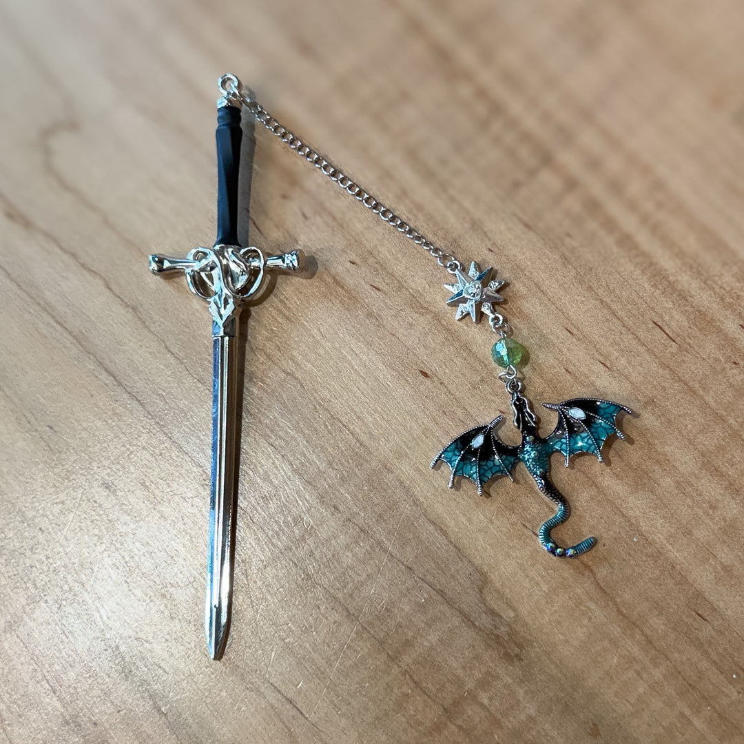 Decorative sword with a dragon charm on a wooden surface