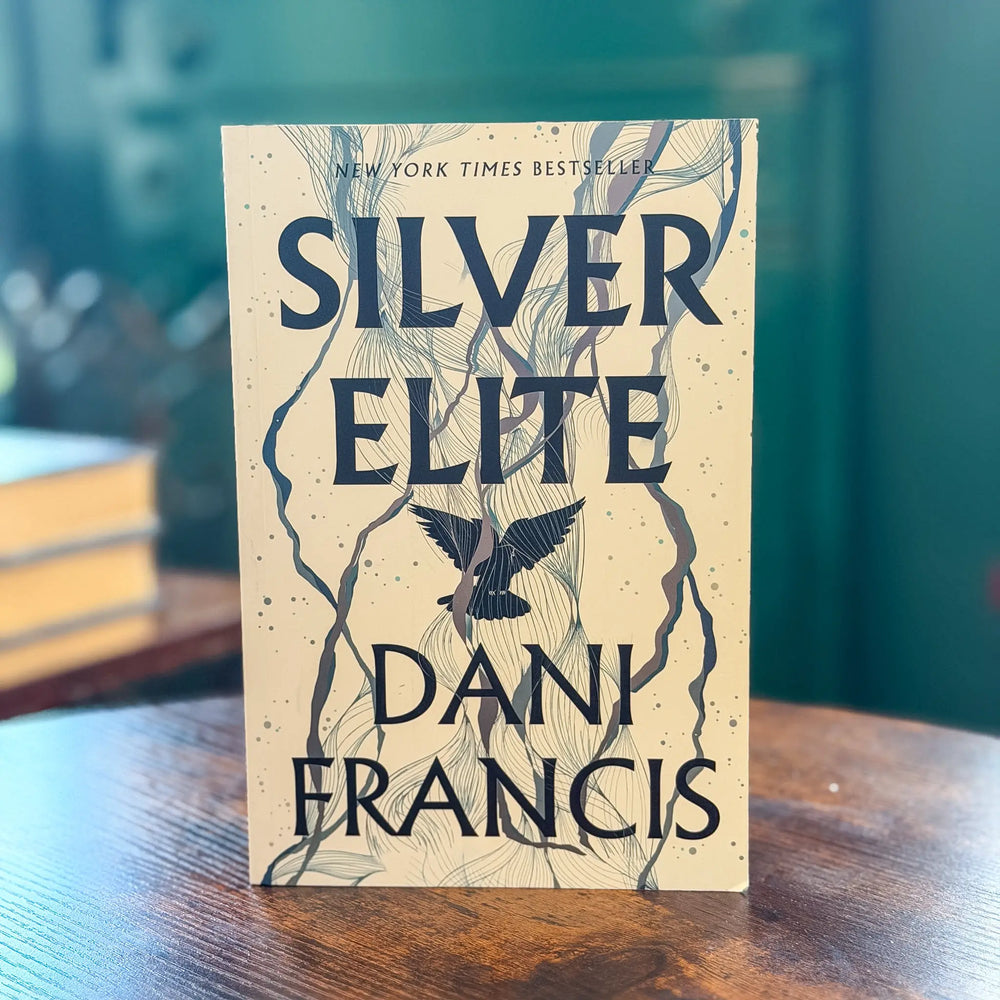 Book titled 'Silver Elite' by Dani Francis on a wooden surface with a blurred background