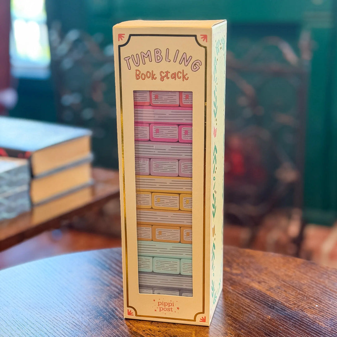 Tumbling Book Stack toy packaging on a wooden surface with books in the background