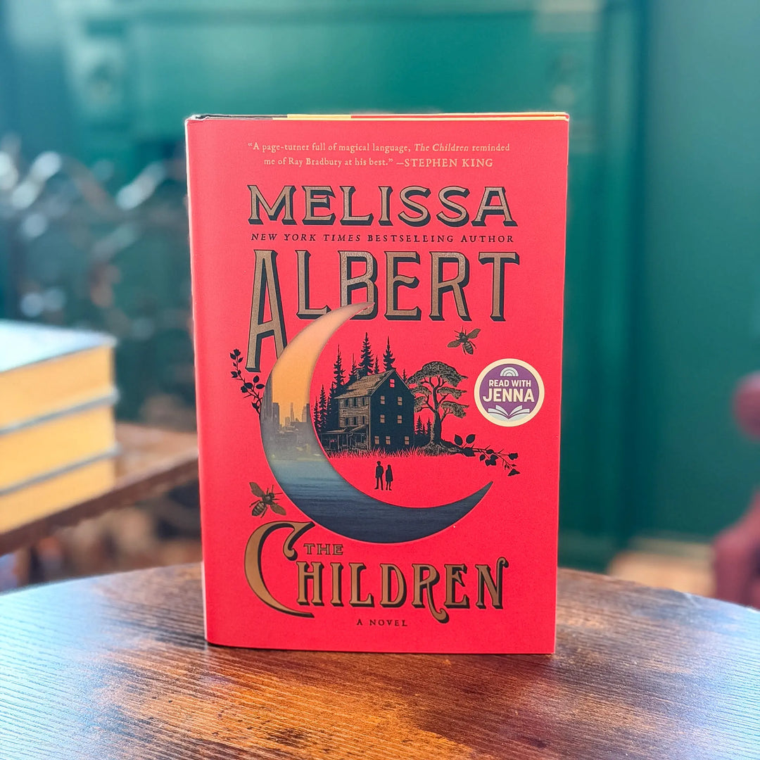 Book titled 'The Children' by Melissa Albert on a wooden table with a blurred background
