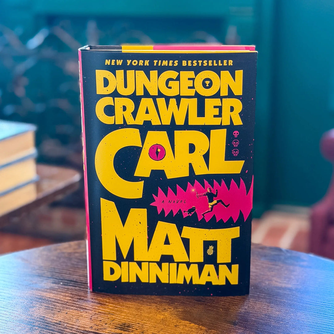 Book titled 'Dungeon Crawler' by Carl Matt Dinniman on a wooden table with a blurred background.