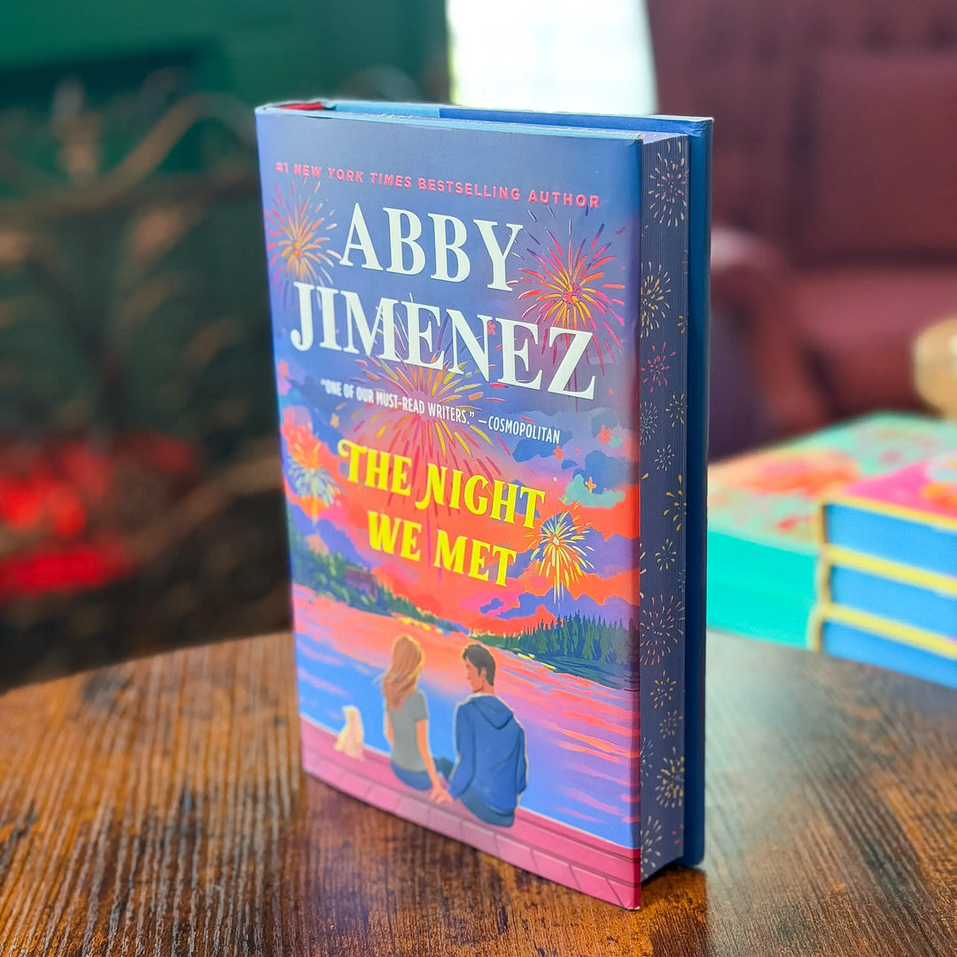 Book titled 'The Night We Met' by Abby Jimenez on a wooden table with a blurred background