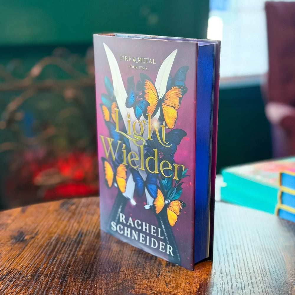 Book titled 'Light Wielder' by Rachel Schneider on a wooden table with a blurred background