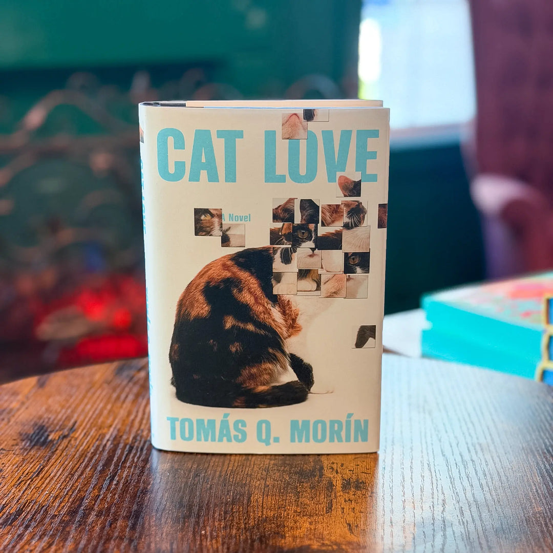 Book titled 'Cat Love' by Tomas Q. Morin on a wooden table with a blurred background