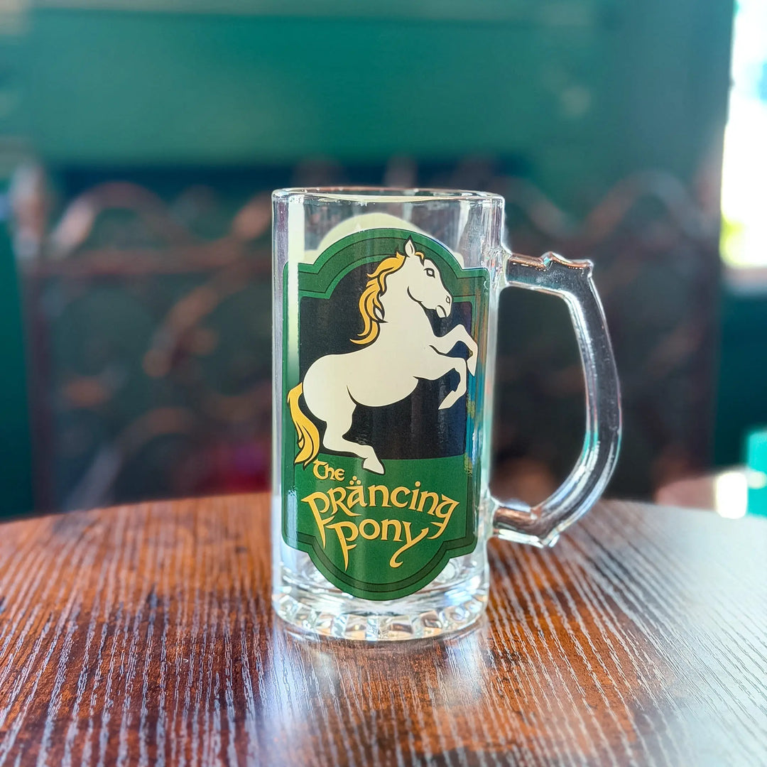 Clear mug with 'The Prancing Pony' logo on a wooden table