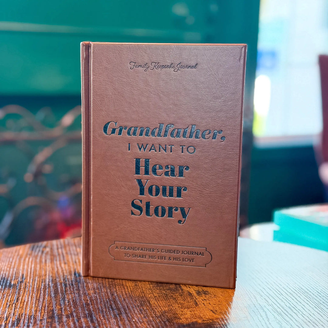 Brown book titled 'Grandfather, I Want to Hear Your Story' on a wooden table with a blurred background