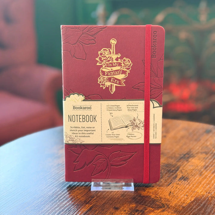 Red notebook with gold embossed design on a wooden table