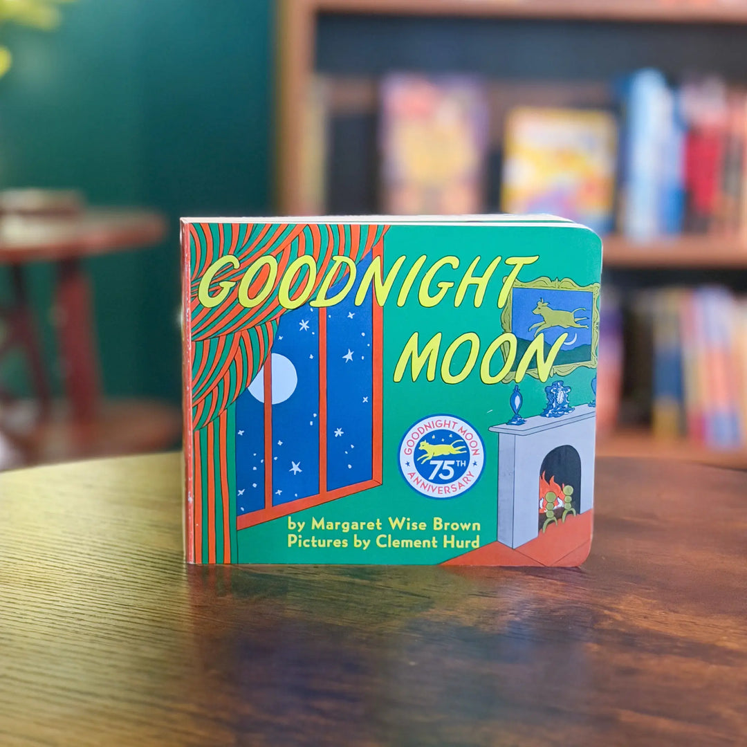 Book titled 'Goodnight Moon' on a wooden table with a blurred bookshelf in the background