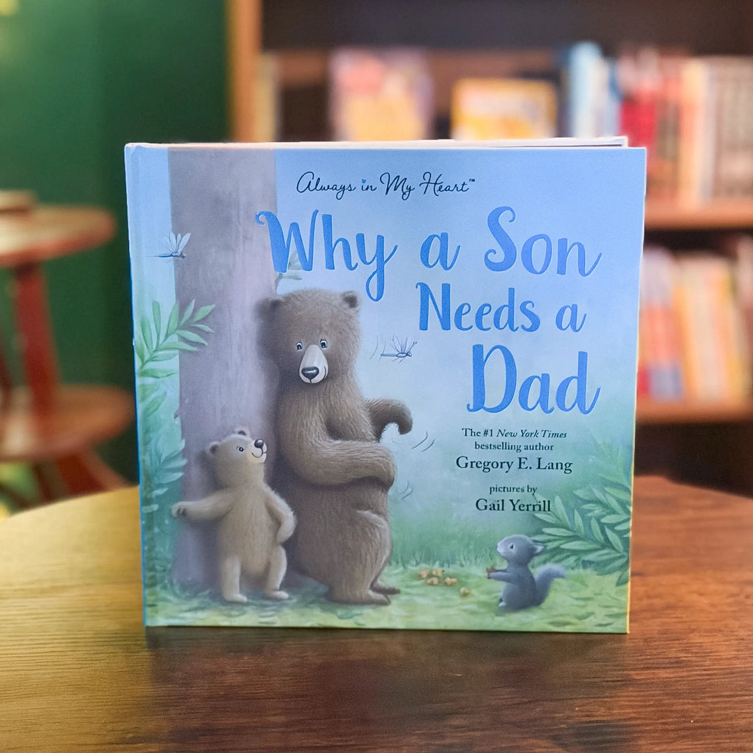 Children's book titled 'Why a Son Needs a Dad' with bear illustrations on a wooden table.