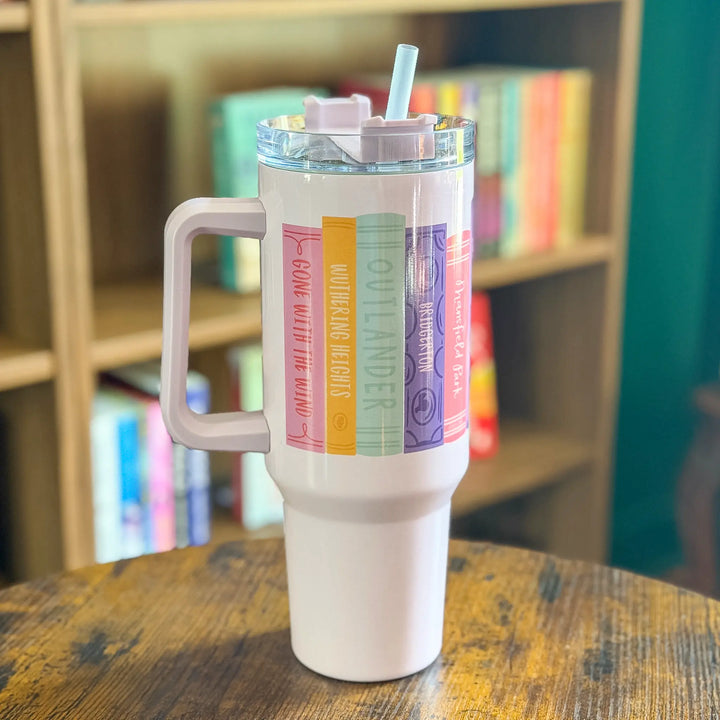 Colorful tumbler with a handle on a wooden surface, blurred bookshelf in the background
