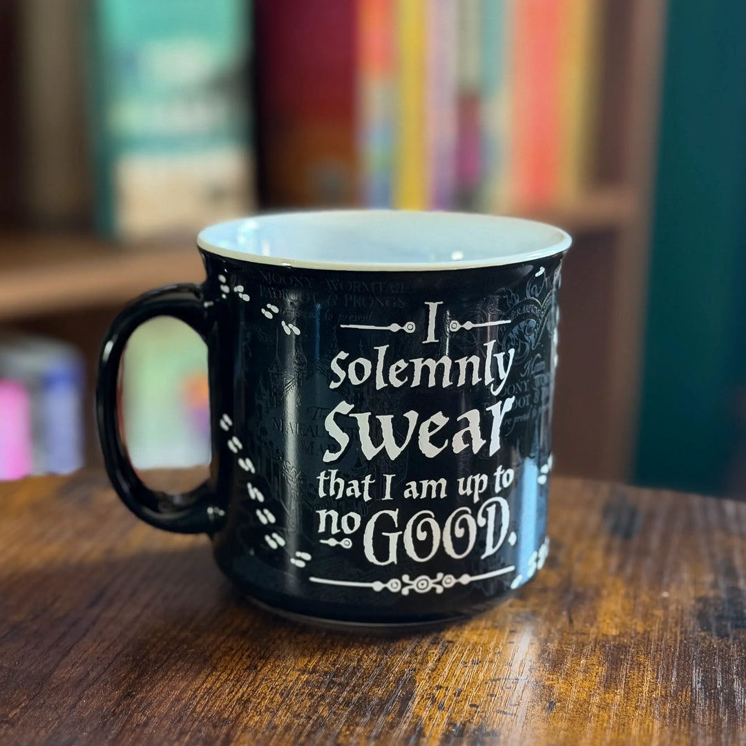 Black mug with text on a wooden surface with a blurred bookshelf background