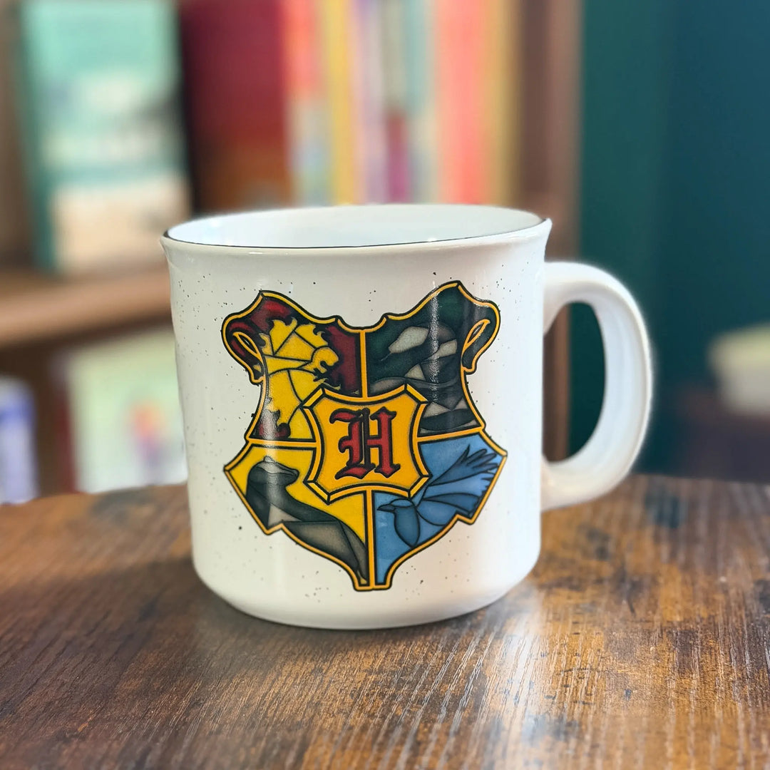 White mug with Hogwarts crest design on a wooden table