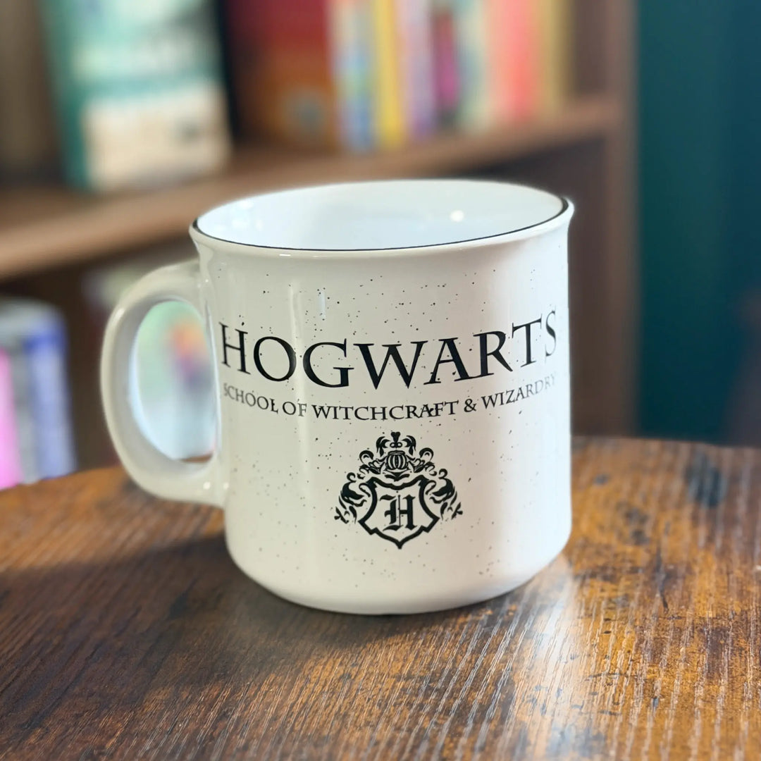 Hogwarts mug on a wooden table with books in the background