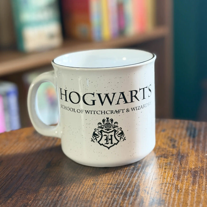 Hogwarts mug on a wooden table with books in the background