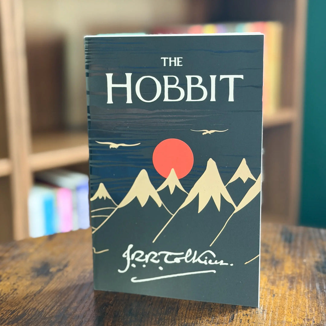 Book titled 'The Hobbit' by J.R.R. Tolkien on a wooden surface with a blurred background.