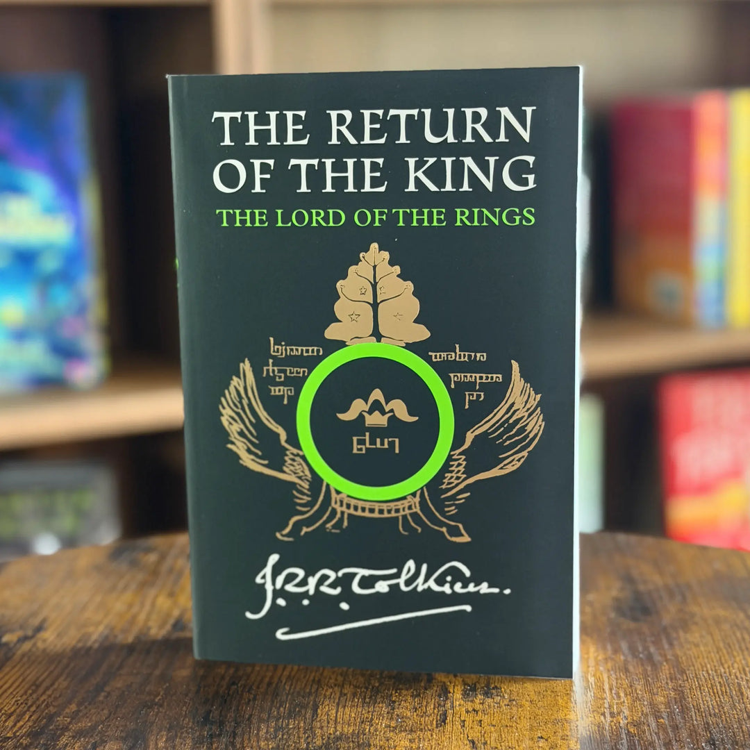 Book titled 'The Return of the King' from 'The Lord of the Rings' series on a wooden surface with blurred bookshelf in the background.