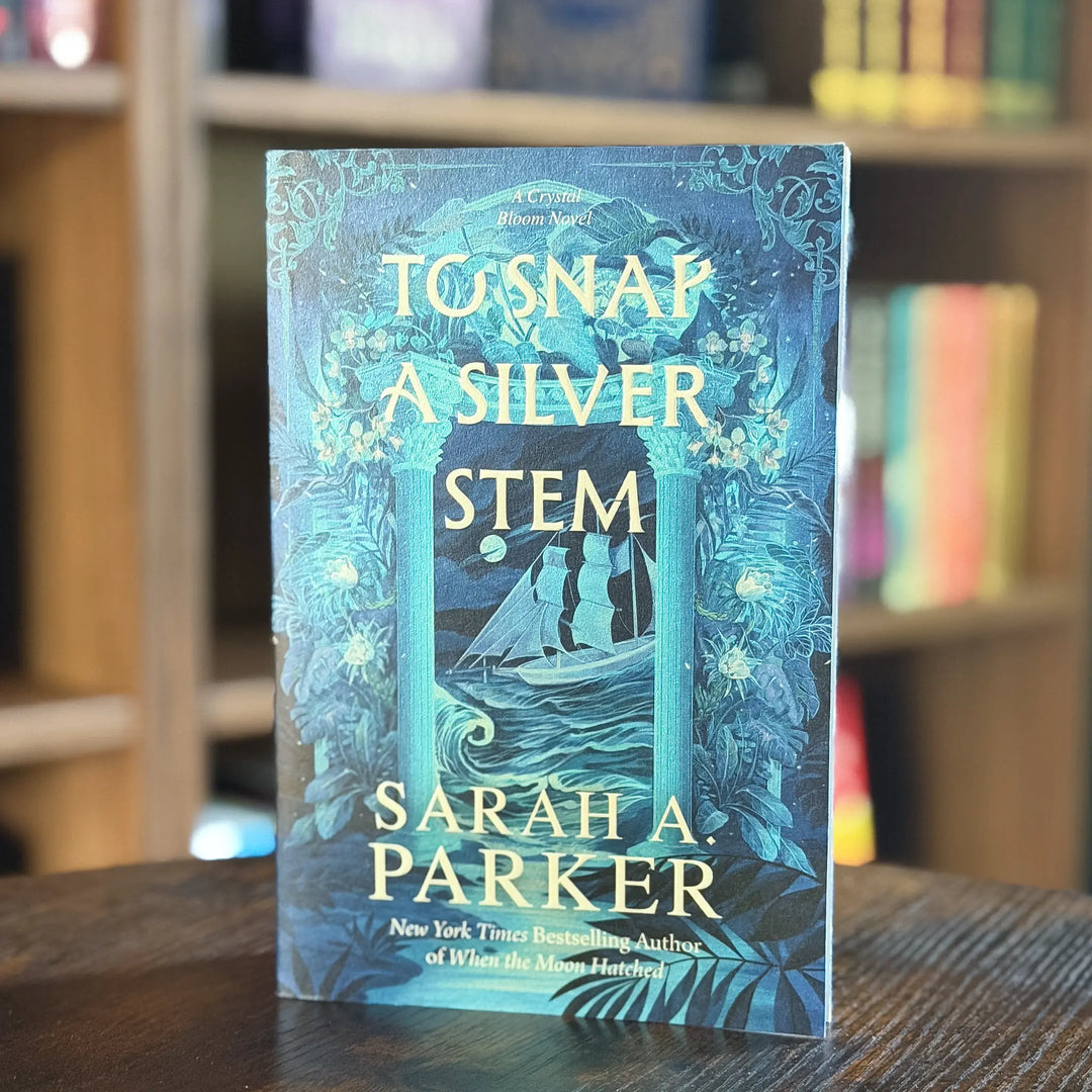 Book titled 'To Snap a Silver Stem' by Sarah A. Parker on a wooden surface with a blurred bookshelf background.