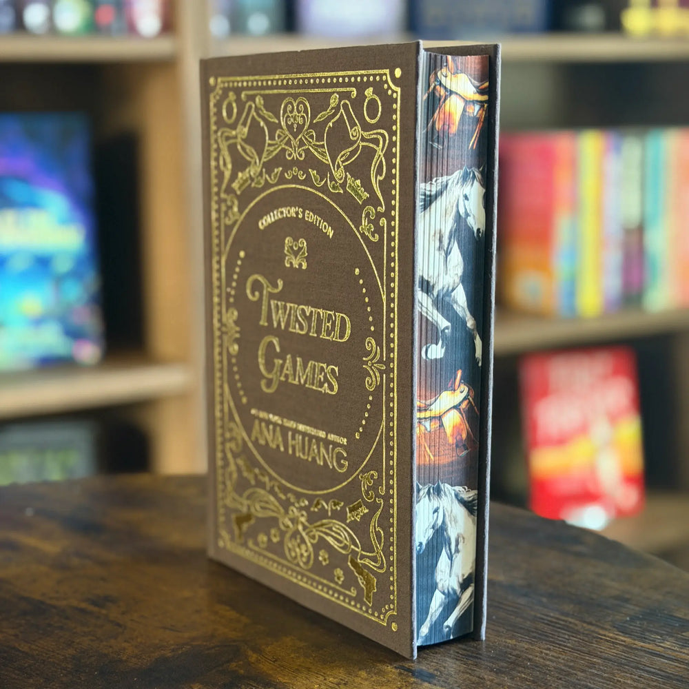 Book titled 'Twisted Games' by Ana Huang on a wooden surface with a blurred bookshelf background.