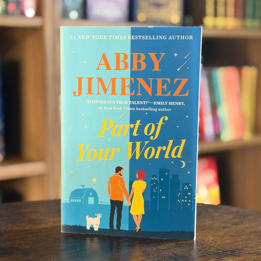 Book titled 'Part of Your World' by Abby Jimenez on a wooden surface with a blurred bookshelf background.