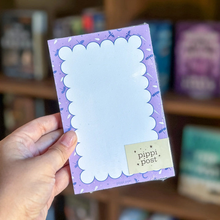 Hand holding a purple notepad with &