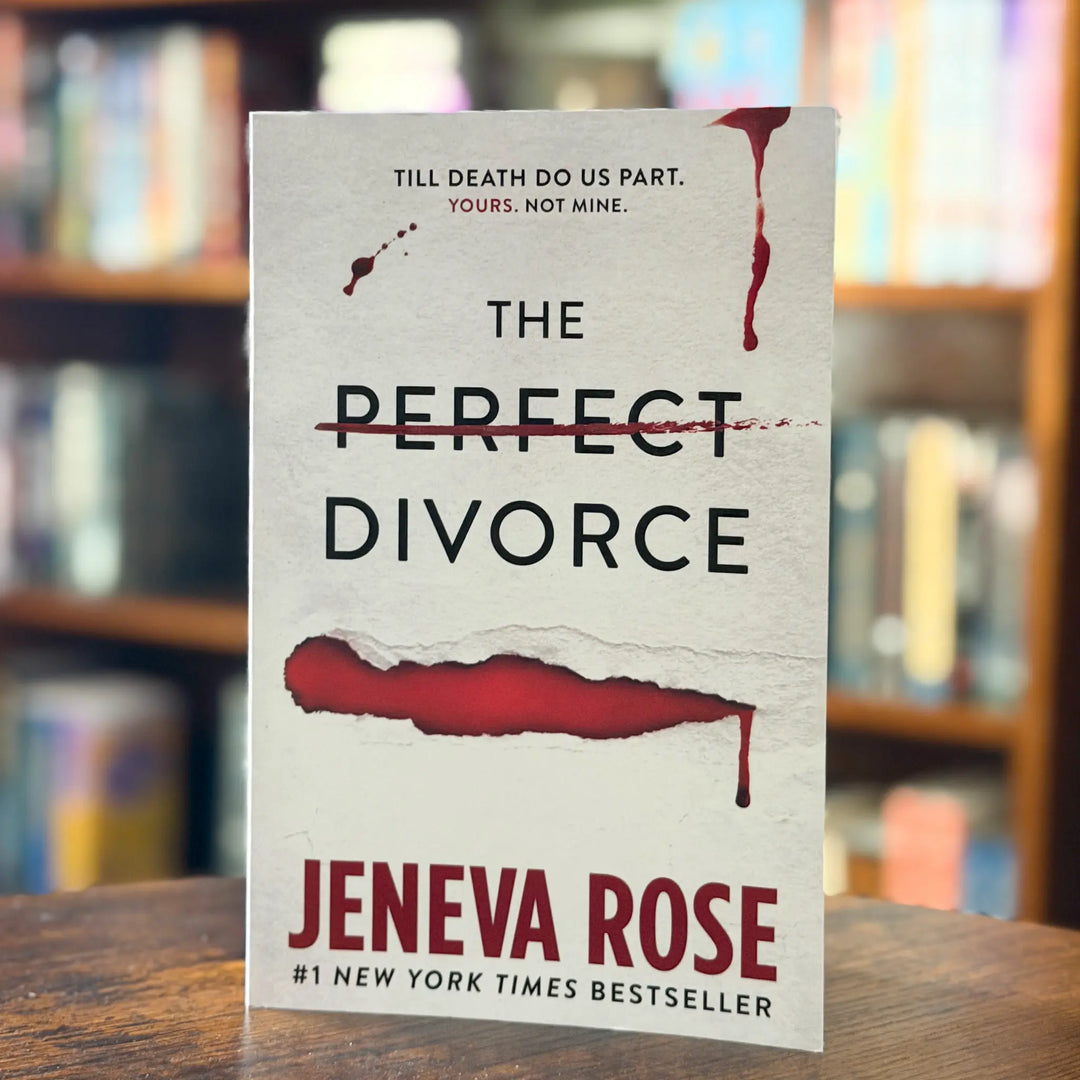 Book titled 'The Perfect Divorce' by Jeneva Rose on a wooden surface with a blurred bookshelf background.