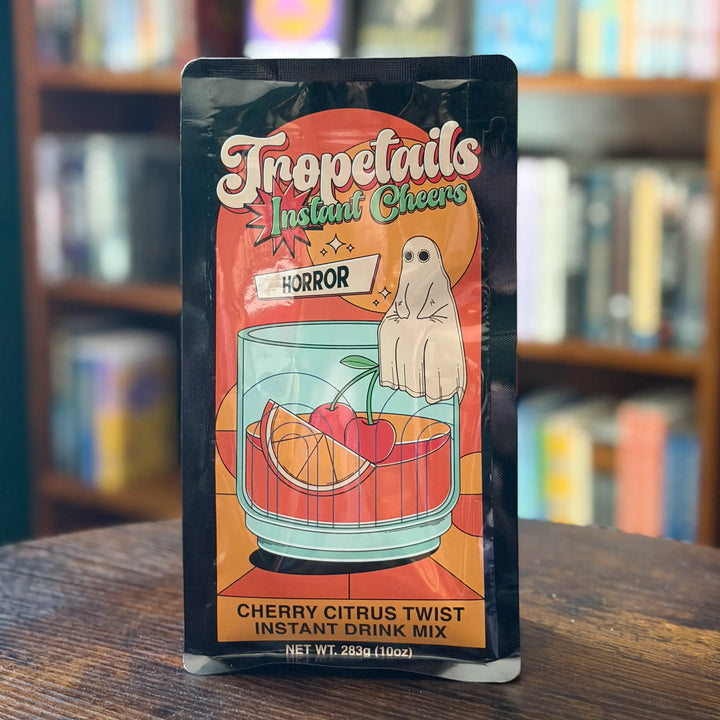 Tropetails Instant Drink Mix package with a ghost and cocktail illustration on a wooden surface.