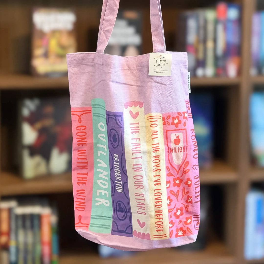 Tote bag with book title designs in front of a bookshelf