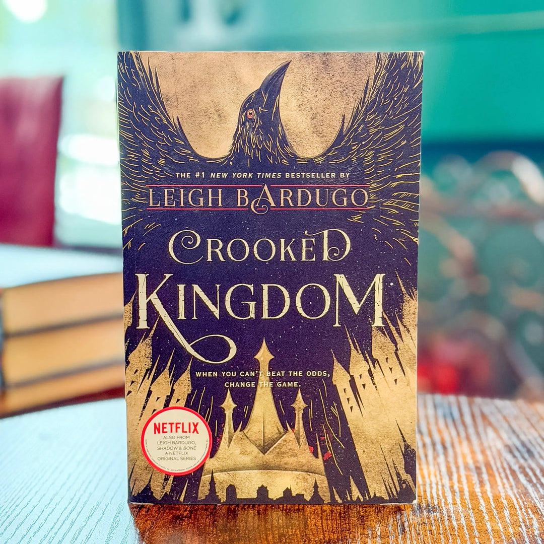 Book titled 'Crooked Kingdom' by Leigh Bardugo with a Netflix logo on a blurred background